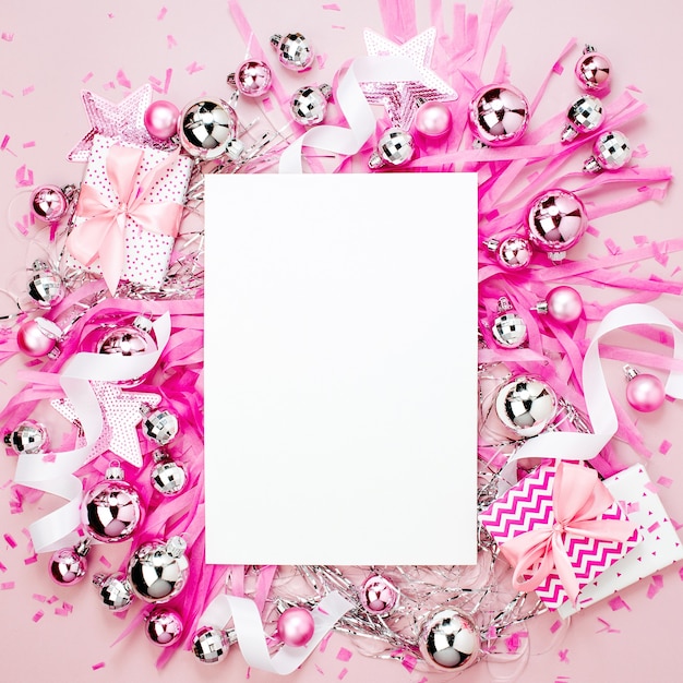 Cartão em branco com bolas de Natal, presentes, fitas e decorações na cor rosa, com espaço de cópia para o texto. Fundo de férias. Camada plana, vista superior