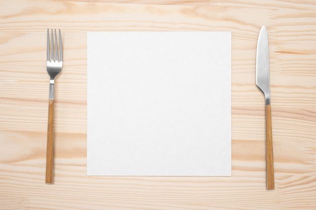 Cartão em branco e talheres na mesa de madeira. página de papel branco de receita de vista superior