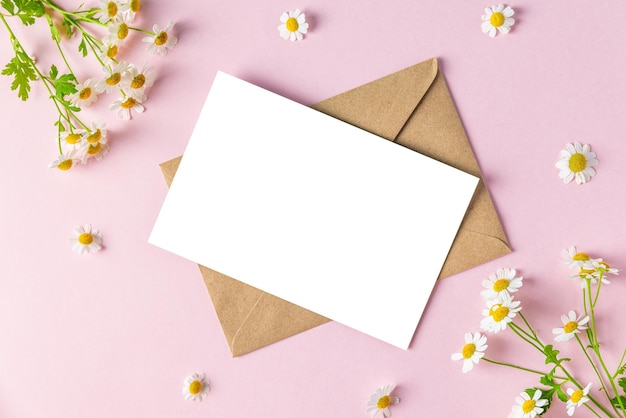 Cartão em branco no quadro feito de flores brancas de camomila em fundo rosa Convite de casamento Mock up