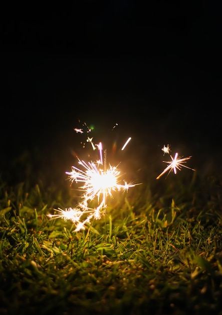 Foto cartão festivo com luzes de guirlanda coloridas brilhantes e fogo de bengali em frasco de vidro no fundo da natureza à noite.