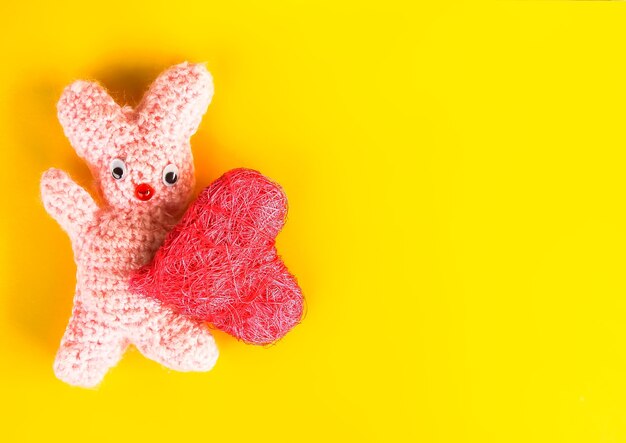 Foto cartão festivo de dia dos namorados com coelhinho de brinquedo artesanal de malha e coração decorativo.