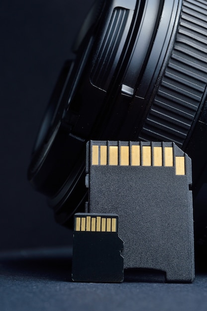 Foto cartão micro sd com adaptador no fundo de uma lente substituível para uma câmera digital.