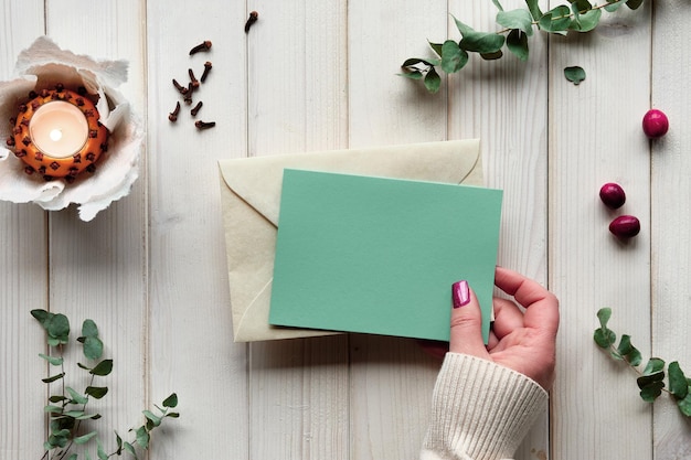 Cartão postal em branco na mão maquete de cartão comemorativo de férias de inverno chá de eucalipto luz em bola de pomander