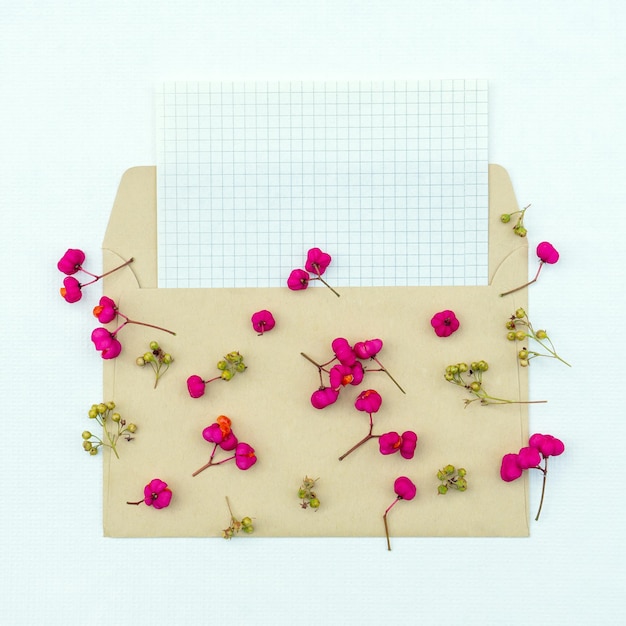 Cartão postal minimalista com pequenas flores vermelhas em um envelope