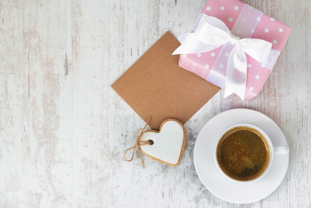 Cartão vazio com uma caixa de presente, biscoito de amor em forma de coração e uma xícara de café.