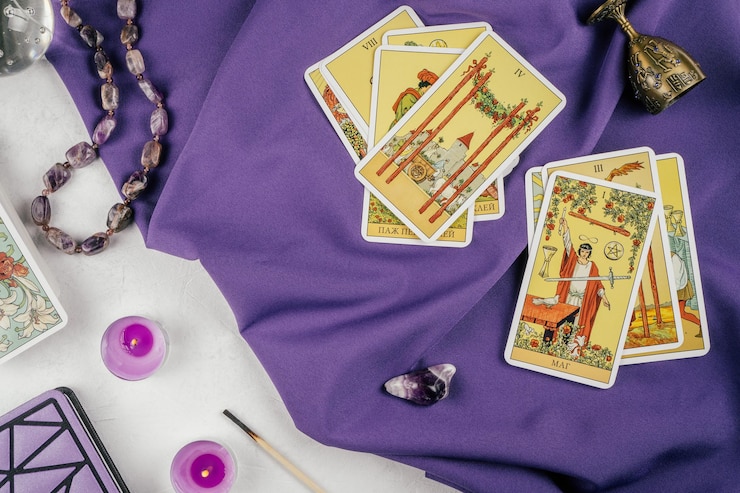 Cartas de tarô espalhadas com a face para cima em um pano roxo na superfície de concreto branco com velas e atributos. Vista do topo. Minsk, Bielo-Rússia, 19.11.2021