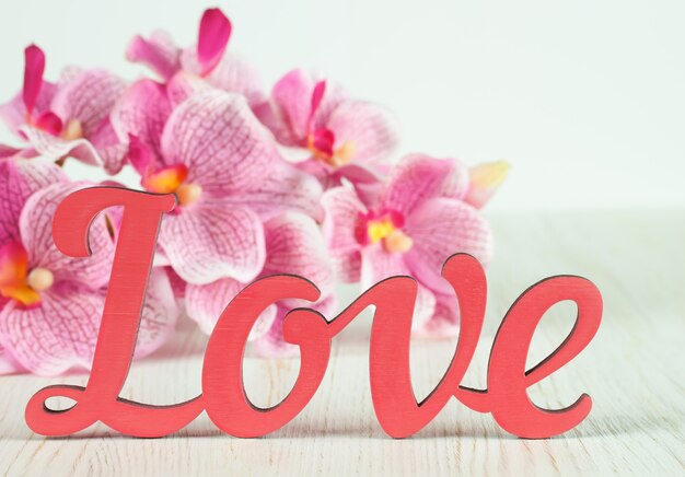 Cartas de San Valentín amor y flores de orquídeas rosadas sobre fondo blanco de madera