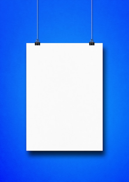 Cartaz branco pendurado em uma parede azul com clipes.