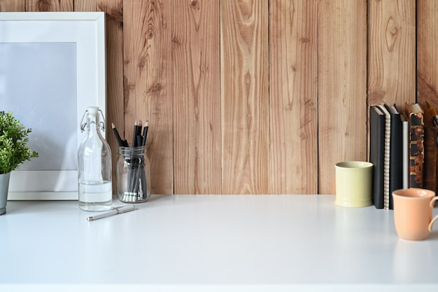 Cartaz de maquete na mesa de madeira branca com uma caneca e acessórios de escritório