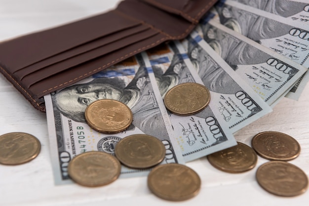 Carteira preta com notas de dólar e moedas de centavo, conceito de poupança