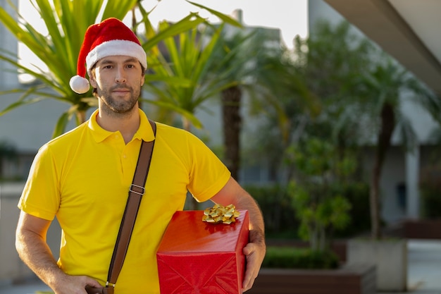 Carteiro brasileiro vestido de papai noel entregando um presente.