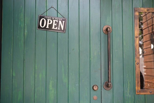 Cartel abierto de bienvenida en la puerta de la tienda orzuelo de tono vintage