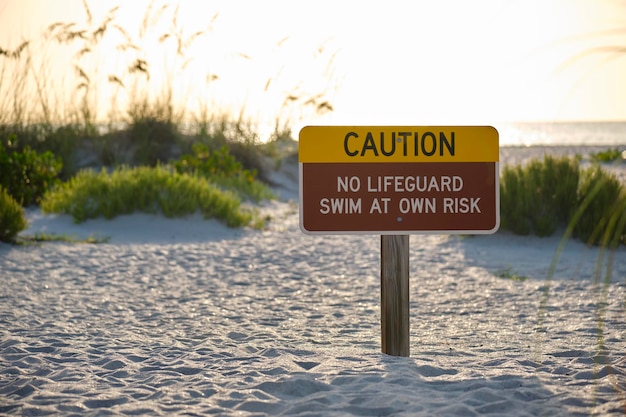 Cartel de advertencia en la playa junto al mar que dice que no hay socorrista de servicio