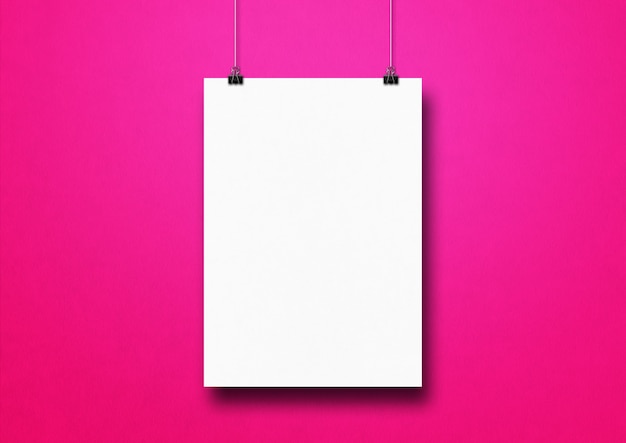 Cartel blanco colgado en una pared rosa con clips.