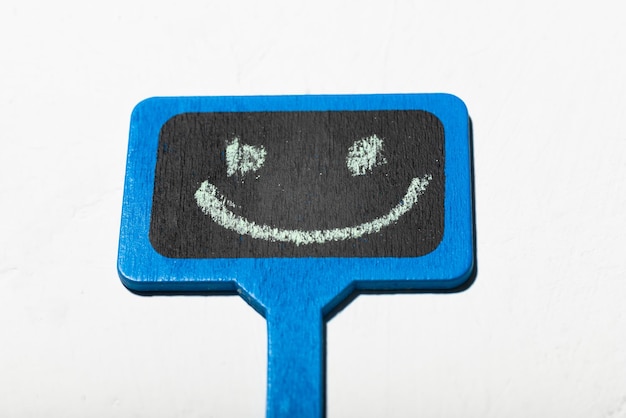 Un cartel con una carita sonriente Cartel de madera azul con una sonrisa positiva sobre un fondo blanco
