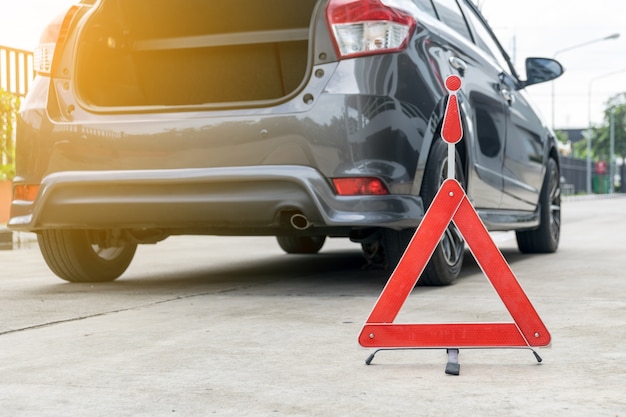 Cartel de coche roto en una carretera con un coche averiado