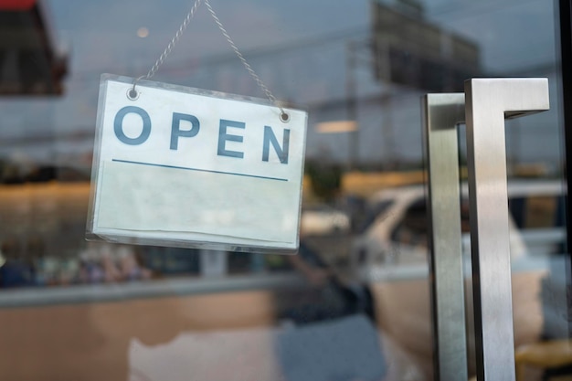 Un cartel comercial que dice 'Abrir' en una cafetería o restaurante colgado en la puerta de entrada