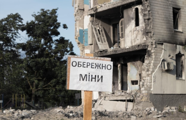 El cartel Cuidado con las minas en el fondo de un edificio residencial destruido
