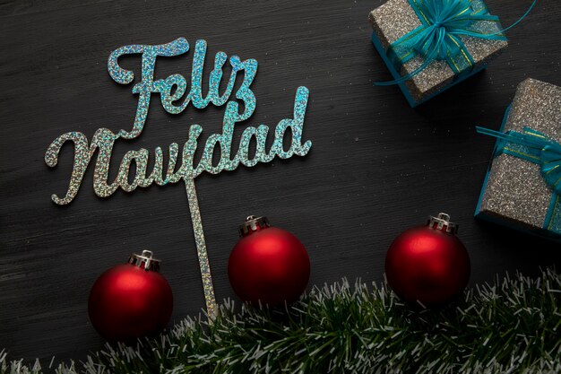 Cartel de feliz navidad con esferas y regalos sobre fondo negro