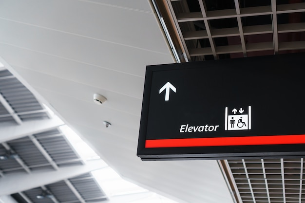 Un cartel con una flecha apuntando al ascensor en la terminal de espera del aeropuerto.