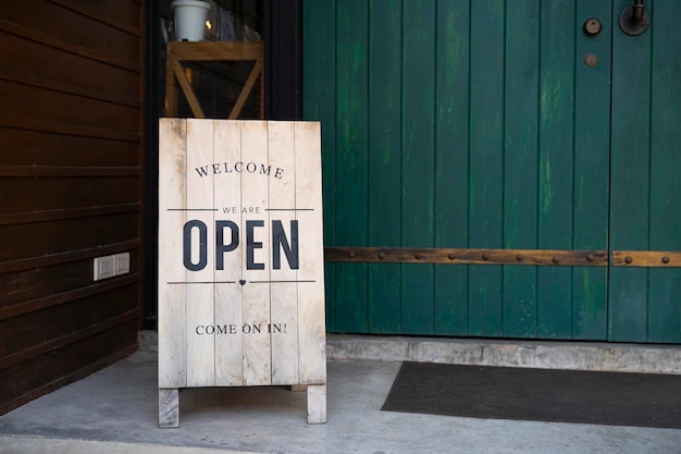 Un cartel de madera con la palabra bienvenida abre el cartel en la puerta de la tienda