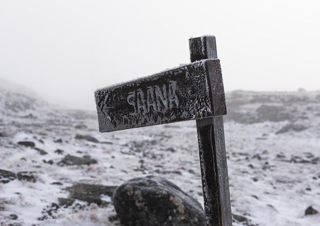 Cartel en la nieve en un brumoso día de otoño Sauna de montaña en Finlandia