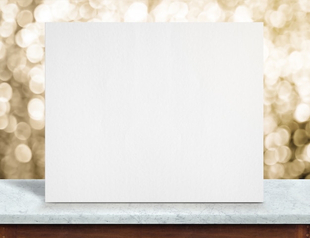 Cartel de papel blanco en blanco sobre mesa de mármol blanco y brillante luz dorada bokeh