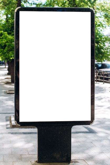 Cartel publicitario vertical de la cartelera de la calle en blanco en fondo del parque de la ciudad.