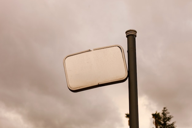 Cartel roto en blanco con un fondo de cielo gris