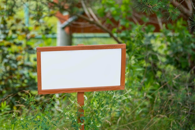 Cartel vacío en el jardín, un cartel de madera con un lugar para el texto se alza contra el fondo de un jardín verde