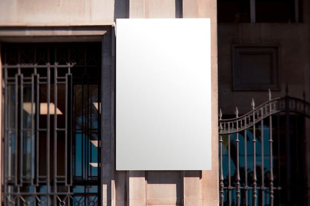 Cartelera de pared blanca rectangular cerca de la puerta de metal