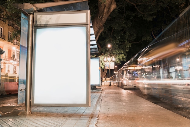 Foto cartelera publicitaria en blanco en la parada de autobús con semáforos borrosos