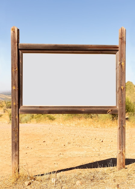 Foto cartelera vacía o letrero hecho con palos de madera en medio del campo vertical