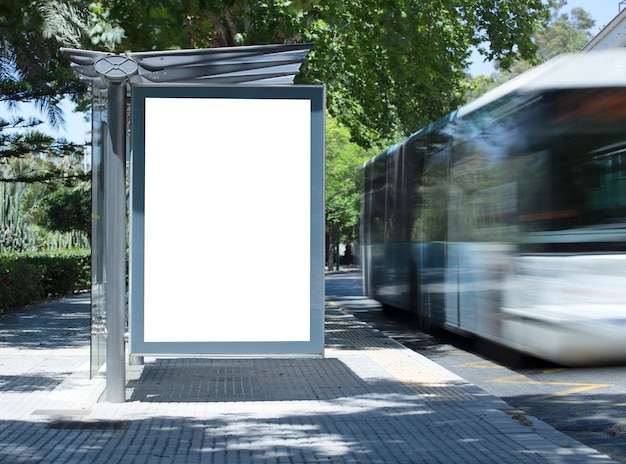 Cartelera vertical en blanco blanco en la parada de autobús en la calle de la ciudad en el fondo de autobuses y ro