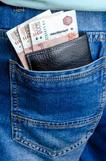 Cartera de cuero con billetes en denominaciones de 5000 rublos en un bolsillo de jeans El concepto de finanzas inversión ahorro en efectivo