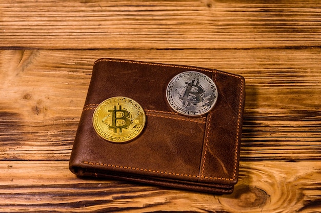 Cartera de cuero marrón y bitcoins en el fondo de madera