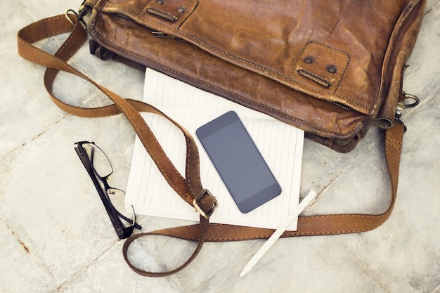 Cartera de cuero marrón en blanco diario de teléfono celular y gafas