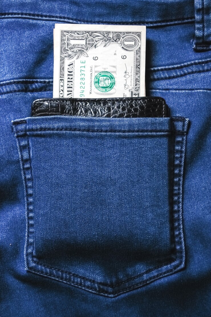Cartera de cuero negro con dinero en la parte posterior de los pantalones vaqueros azul textura de mezclilla bolsillo