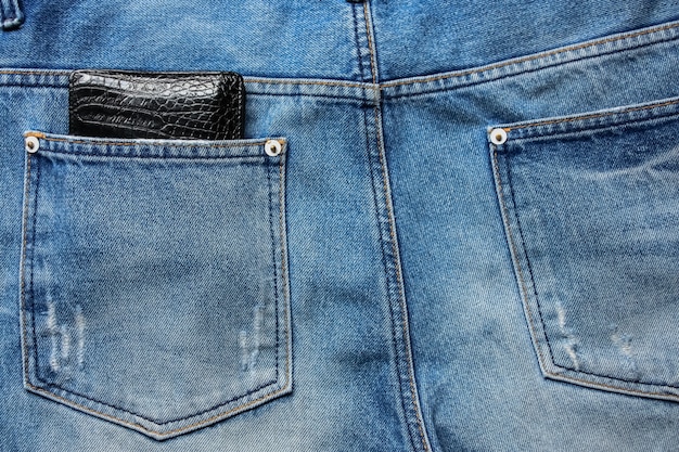 Cartera de cuero negro en la parte posterior de los pantalones vaqueros azules textura de fondo de mezclilla bolsillo.