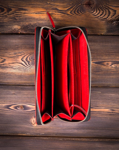 Cartera de cuero roja abierta y vacía sobre un fondo de madera rústica