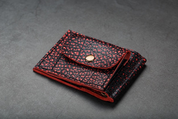 Cartera de cuero rojo y negro sobre una mesa negra.