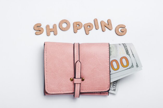 Cartera de cuero rosa con billetes y word shopping