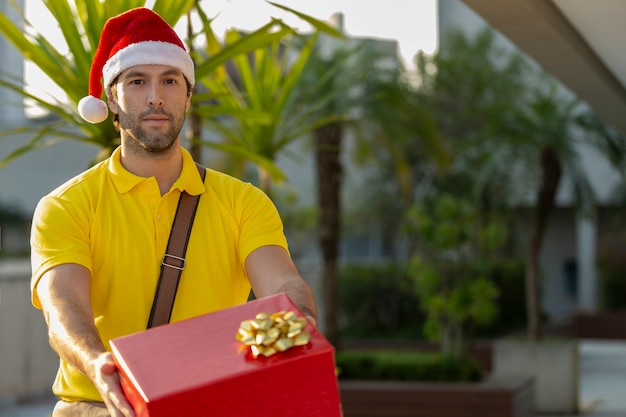 Cartero brasileño disfrazado de Santa Claus entregando un regalo. Se entrega la compra en línea.