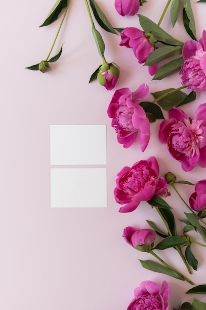 Cartões de convite de papel em branco com espaço para cópia Buquê de flores de peônia rosa em fundo rosa pastel neutro e elegante Composição floral mínima vista superior plana