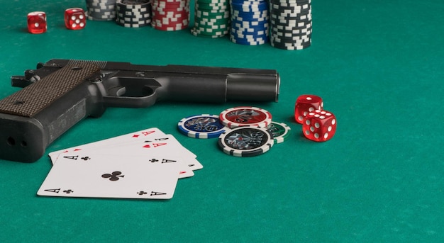 Cartões de fichas de pôquer e arma em um fundo verde o conceito de jogo e entretenimento