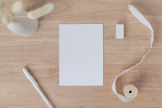 Cartões de papel em branco, maquete de convite de cartão em branco com grama seca de cauda de coelho em vaso em uma mesa de madeira, fundo de mesa de madeira, composição mínima de mesa de madeira no local de trabalho, postura plana, maquete