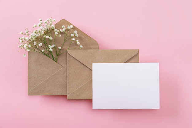 Foto cartões de saudação em branco e envelopes com gypsophila em fundo rosa cartões de folha de papel em branco com espaço de cópia de maquete composição mínima no local de trabalho vista superior plana leiga