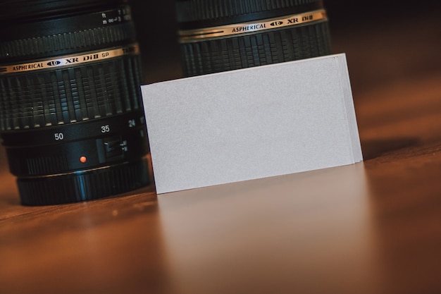 Foto cartões de visita brancos vazios em branco ao lado das lentes das câmeras