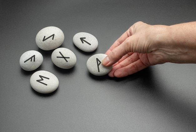 Cartomancia com símbolos na pedra mão segurando pedras rúnicas nórdicas com símbolos pretos