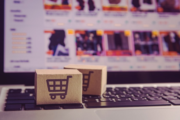 Foto cartones de papel con el logotipo de un carrito de compras en un teclado portátil.